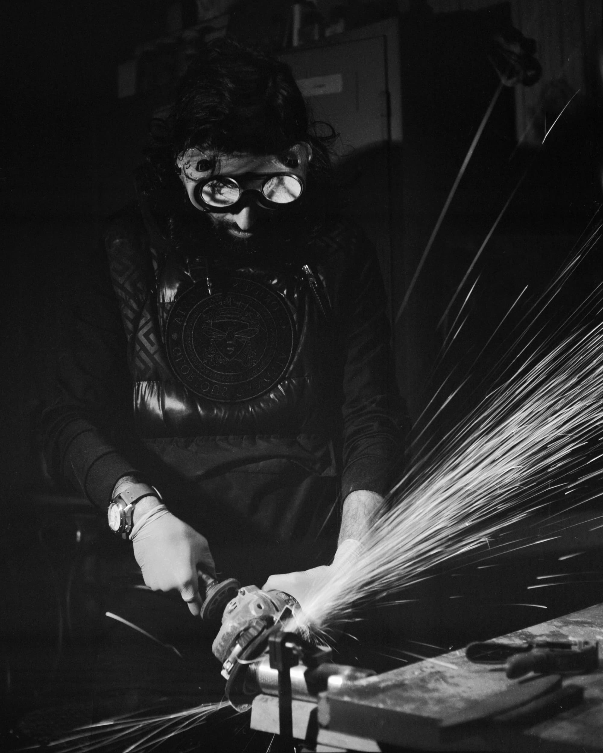 Black and white portrait of man grinding metal part with sparks flying around on Fuji Neopan Across II film.